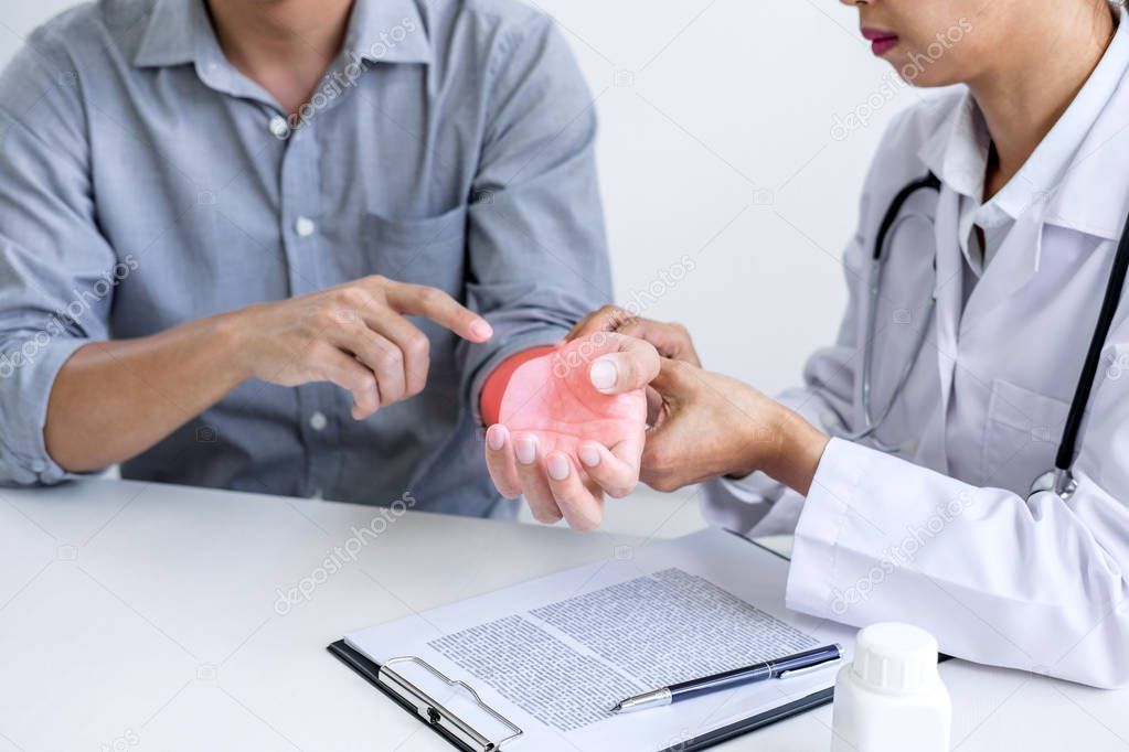 Doctor in white coat taking and checking the Patient's wrist pain during the examination.
