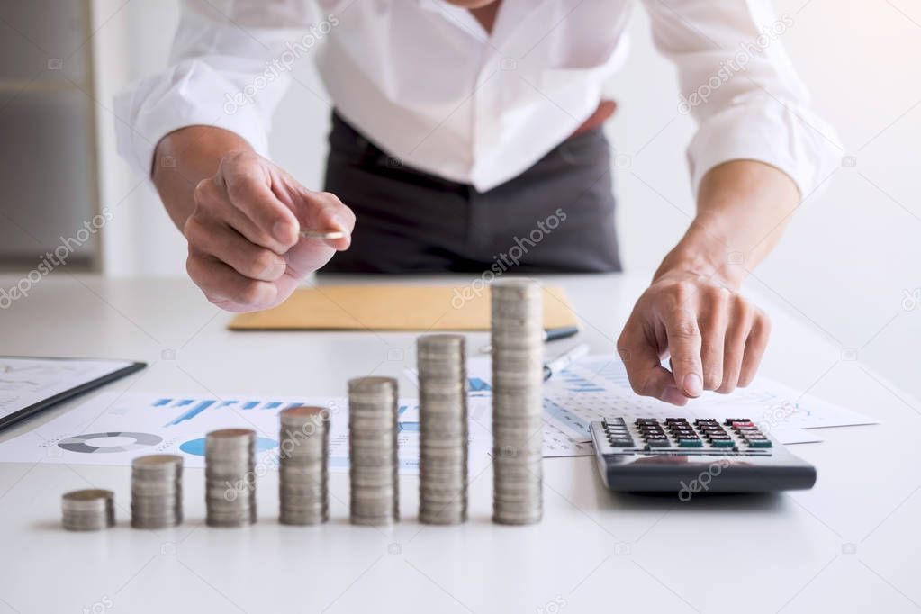 Business accountant or banker, businessman calculate and analysis with stock financial indices and putting growth stacking coin and financial costs wisely and carefully, investment and saving concept.