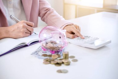 Rapor yazma ve hesap makinesi analizi iş yatırım stratejisi için para sikke ve Doları, mali kavramı gelir ile kullanarak kumbara para koyarak iş kadını.
