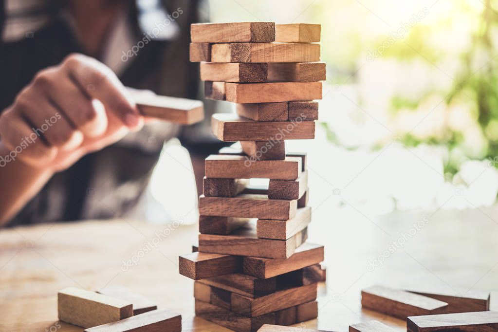 Images of hand of businesspeople placing and pulling wood block on the tower, Alternative risk concept, plan and strategy in business, Risk To Make Business Growth Concept With Wooden Blocks.