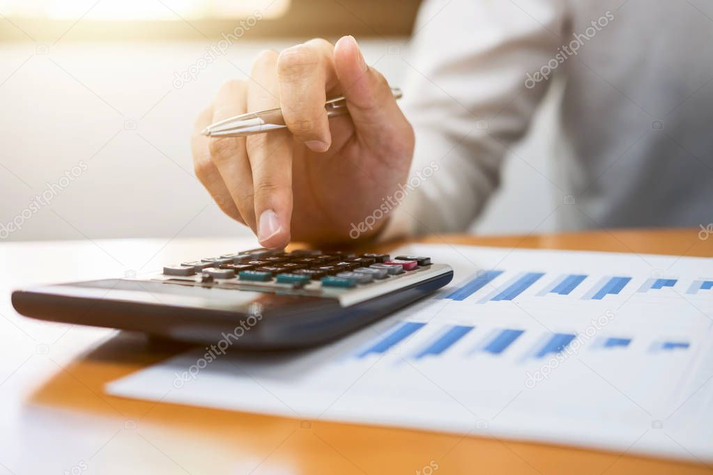 Male accountant calculations and analyzing financial graph data with calculator, Financing, Accounting, Doing finance, Economy, Savings Banking Concept.