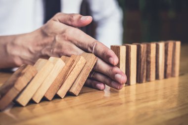 İş dünyası için strateji ve başarılı müdahale kavramı, iş adamı eli Devrilen tahtadan Domino taşları sürekli devrilmezse risk almayacak.