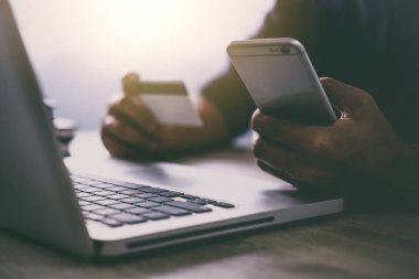 Dizüstü bilgisayar yazmaya ve online alışveriş ve ödeme kredi kartı, Online ödeme ve alışveriş kavramı için smartphone kullanarak adam.