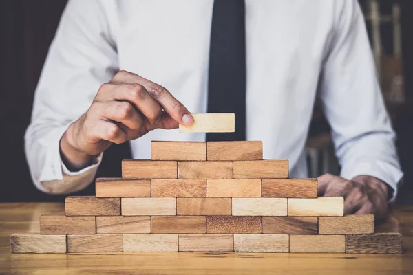 Risk To Make Business Growth Concept With Wooden Blocks, hand of man has piling up and stacking a wooden block, Alternative risk concept, plan and strategy in business.