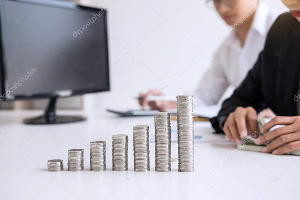 Business accountant or banker, Two business partner analysis with stock financial indices and growth stacking coin and financial costs wisely and carefully, investment and saving concept.