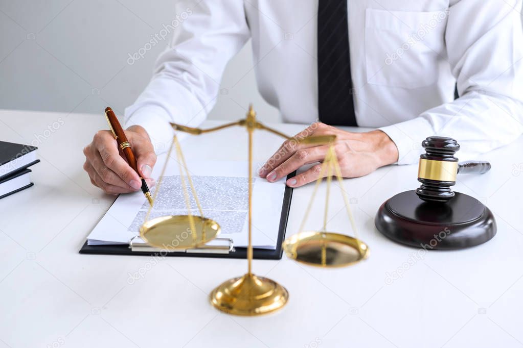 Businessman or lawyer working on a documents, judge gavel with Justice lawyers at law firm in background, Legal law, advice and justice concept.