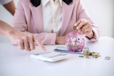 İki rapor yazma ve hesap makinesi analizi iş yatırım stratejisi için para sikke ve Doları, mali kavramı gelir ile kullanarak kumbara içine koyarak paralar çiftler.