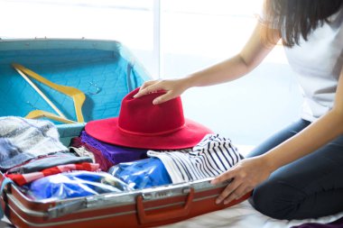 Seyahat ve tatil kavramı, mutluluk genç kadın elbiselerini ve malzeme bir sürü bavul yatak içine ambalaj tatil seyahat ve yolculuk yolculuk için hazırlamak.