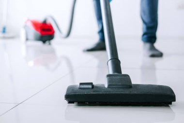 Temizlik ve ev işleri kavramı, bir elektrik süpürgesi katta evde kullanarak mavi kauçuk eldiven mutlu genç adam Temizleme.