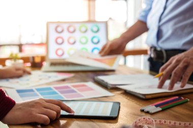 İki genç profesyonel moda tasarımcısı meslektaşları çalışma ve işyeri dizüstü bilgisayar, dijital tablet ve renk şemaları, moda tasarımcısı şık konsept çizimler giyim için çizim proje.