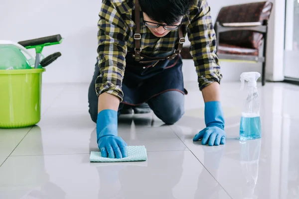 stock image Husband housekeeping and cleaning concept, Happy young man in blue rubber gloves wiping dust using a spray and a duster while cleaning on floor at home.