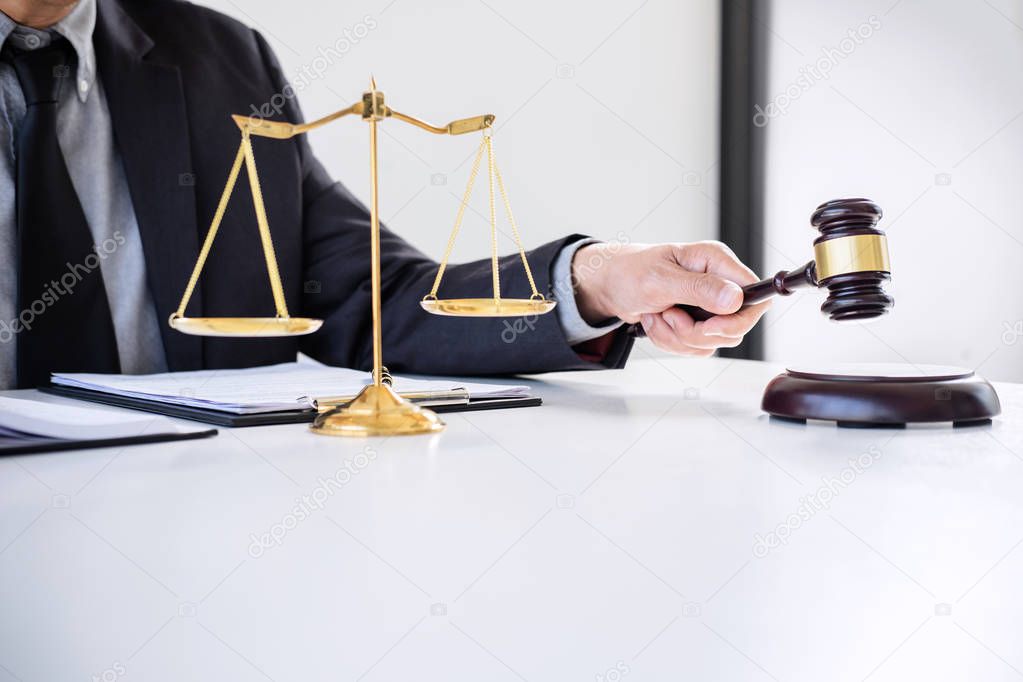 Male lawyer or judge working with Law books, gavel, report the case on table in modern office, Law and justice concept.