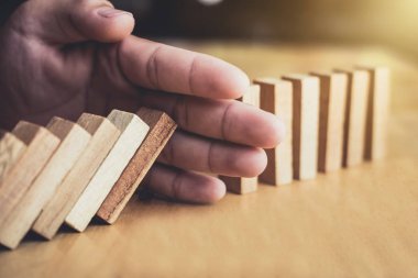 İş dünyası için strateji ve başarılı müdahale kavramı, iş adamı eli Devrilen tahtadan Domino taşları sürekli devrilmezse risk almayacak.