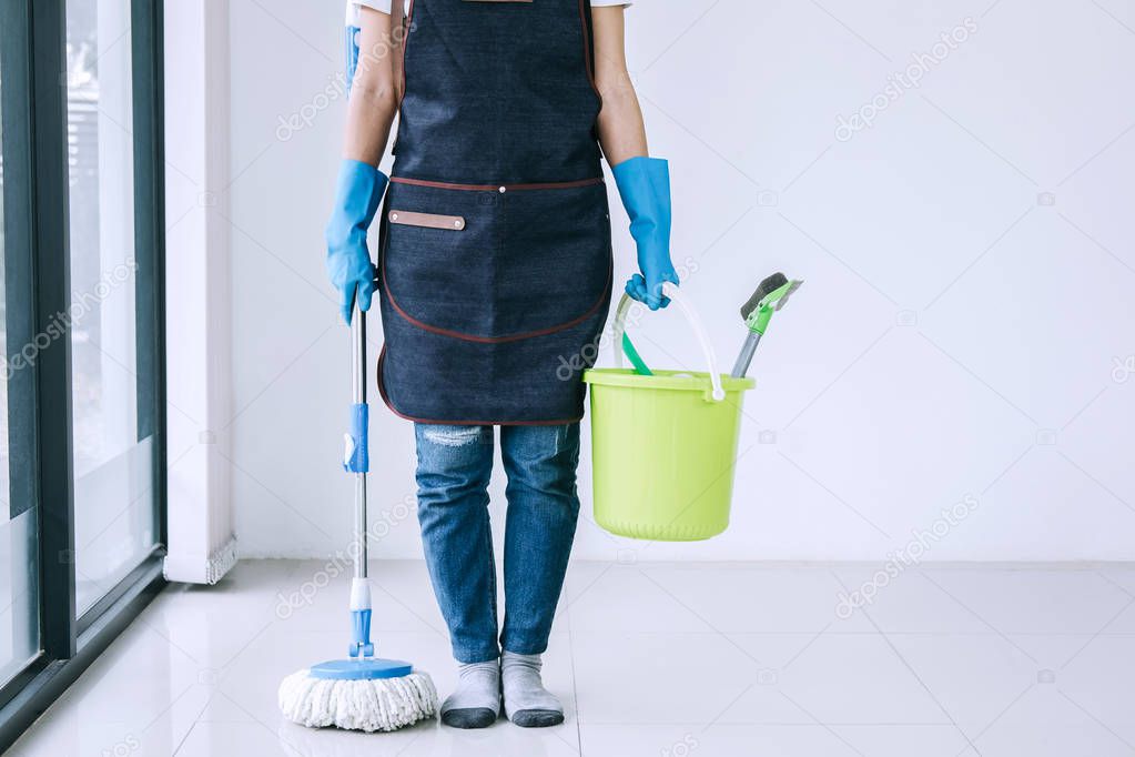 Housekeeping and cleaning concept, Happy young woman in blue rubber gloves holding mop and plastic bucket with brushes while prepare cleaning on floor at home.