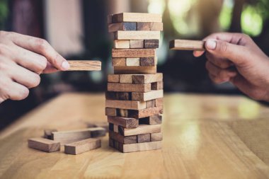 El ahşap blok yerleştirme kule, ortak yönetimi, ahşap oyun, alternatif risk kavramı, plan ve strateji iş oynayan genç zeki işadamı yönetici işbirliği.