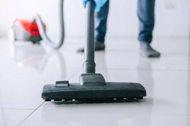Temizlik ve ev işleri kavramı, bir elektrik süpürgesi katta evde kullanarak mavi kauçuk eldiven mutlu genç adam Temizleme.
