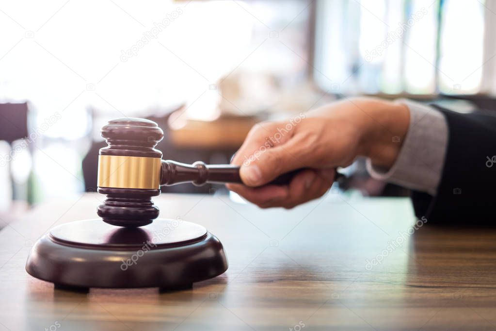 Male lawyer or judge hand's striking the gavel on sounding block, working at courtroom, Law and justice concept.