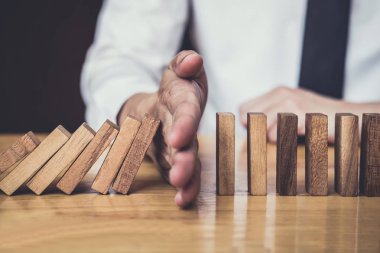 İş dünyası için strateji ve başarılı müdahale kavramı, iş adamı eli Devrilen tahtadan Domino taşları sürekli devrilmezse risk almayacak.