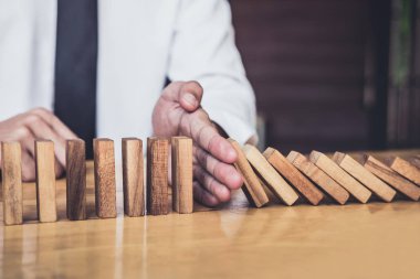 İş dünyası için strateji ve başarılı müdahale kavramı, iş adamı eli Devrilen tahtadan Domino taşları sürekli devrilmezse risk almayacak.