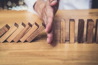 İş dünyası için strateji ve başarılı müdahale kavramı, iş adamı eli Devrilen tahtadan Domino taşları sürekli devrilmezse risk almayacak.