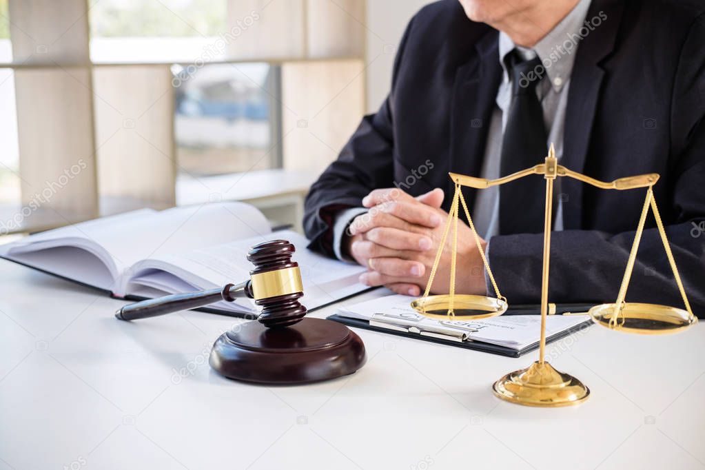 Male lawyer or judge working with Law books, gavel, report the case on table in modern office, Law and justice concept.