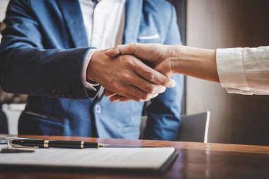 Emlakçı ve müşteriler el sıkışıyor. Ev sigortası, yatırım kredisi, tokalaşma ve başarılı anlaşmayla ilgili bitirilen sözleşmeyi kutluyorlar..