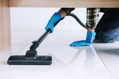 Temizlik ve ev işleri kavramı, bir elektrik süpürgesi katta evde kullanarak mavi kauçuk eldiven mutlu genç adam Temizleme.