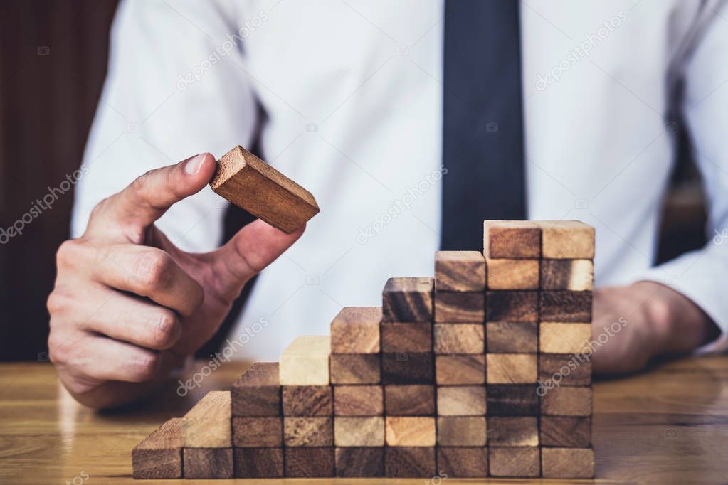Risk To Make Business Growth Concept With Wooden Blocks, hand of man has piling up and stacking a wooden block, Alternative risk concept, plan and strategy in business.
