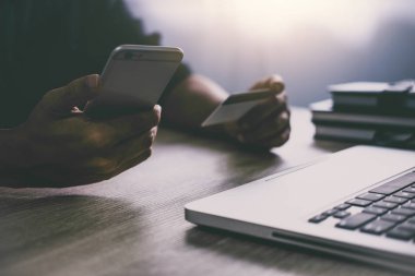 Dizüstü bilgisayar yazmaya ve online alışveriş ve ödeme kredi kartı, Online ödeme ve alışveriş kavramı için smartphone kullanarak adam.