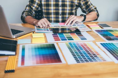 Genç yaratıcı grafik tasarımcı renk renk örneği örnekleri grafik iş araçları ve aksesuarları işyerinde boyama seçimi için seçmek için grafik tablet kullanma.
