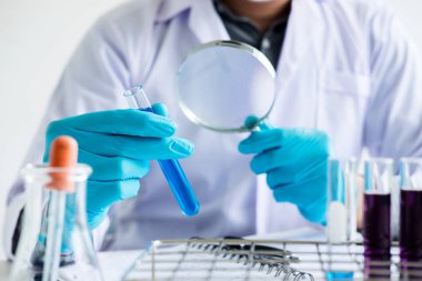 Biyokimya Laboratuvarı araştırma, bilim adamı veya tıbbi laboratuarda çalışan cam ekipman üzerinde test tüpü ile reaktif renk sıvı damla ile tutarak önlük içinde.