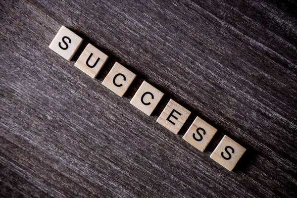 Ahşap arka plan üzerinde ahşap küpleri ile kelime başarı ile bulmaca tarafından sunulan konsept.