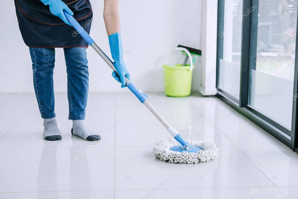 Housekeeping and cleaning concept, Happy young woman in blue rubber gloves wiping dust using mop while cleaning on floor at home.