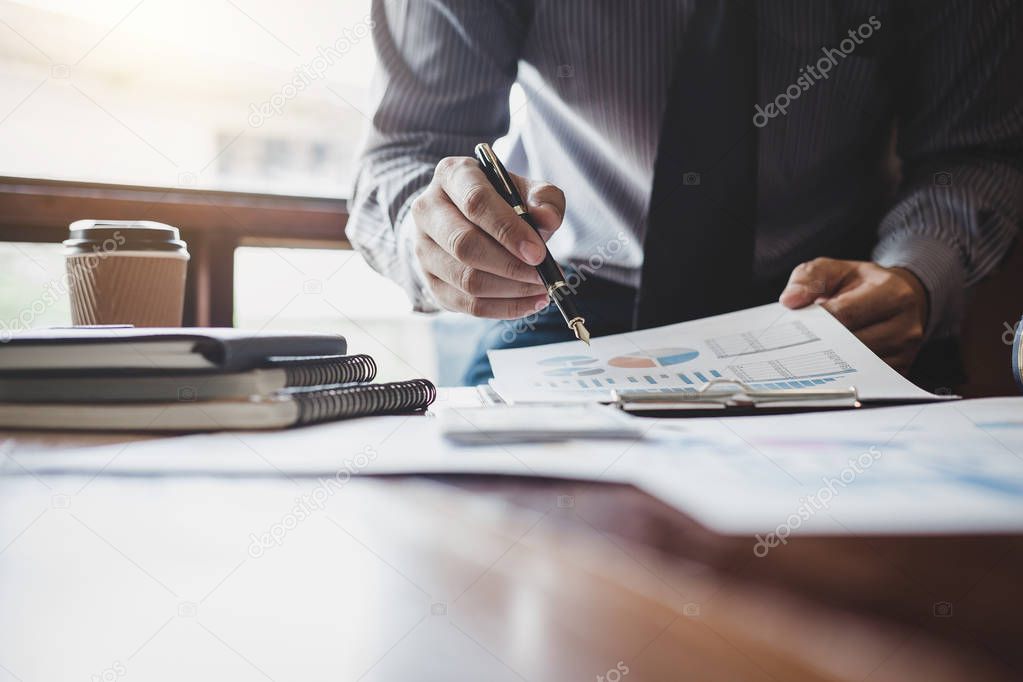 Businessman pointing at graph and chart to analysis use for plans to improve quality, business finances and accounting concept.