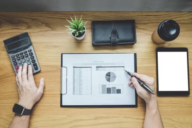 Bir grafik belge mali rapor ve analiz hesaplama maliyet ofis masası, hesap makinesiyle ve diğer nesnelerin çevresine, üstten görünüm çalışma alanı ve boş ekran tablet üzerinde çalışan iş adamı.