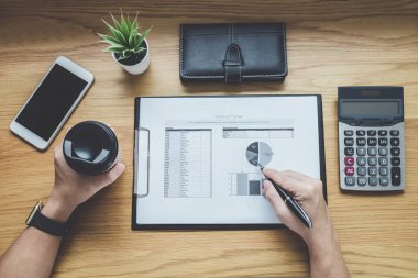 İşadamı bir grafik belge mali rapor ve analiz hesaplama maliyet ofis masası, hesap makinesiyle ve diğer nesnelerin çevresine, üstten görünüm çalışma alanı üzerinde çalışma.