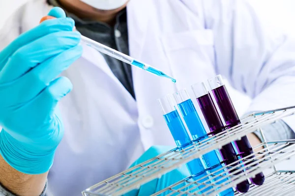 生化学研究所の研究 科学者や研究室で働くガラス機器を介して色液のドロップで試薬を試験管を保持している白衣の医療 — ストック写真