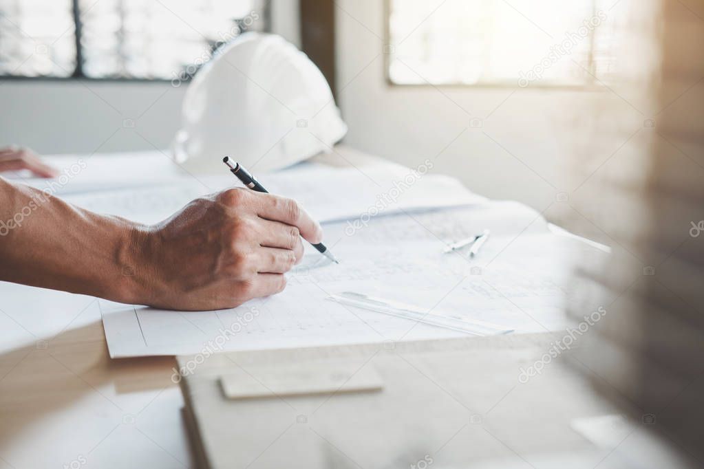 Construction concept, Hands of architect or engineer working for new project plan on blueprint, model building and engineering tools in working site.