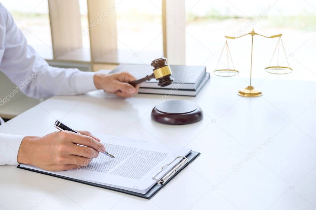 Businessman or lawyer working on a documents, judge gavel with Justice lawyers at law firm in background, Legal law, advice and justice concept.