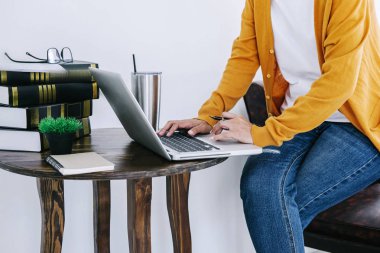 Mutlu rahat Genç Asyalı kadın serbest yazar olarak masanın üzerinde bir laptop ve belge rapor kullanarak ev veya küçük ofis çalışma.