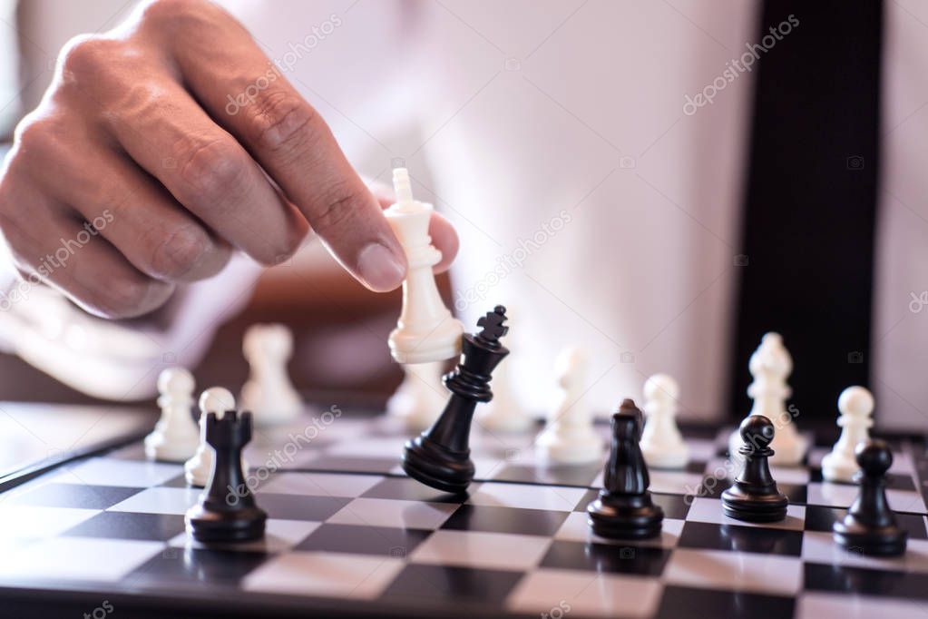 Hand of confident businessman use king chess piece white playing chess game to crash overthrow the opposite team and development analysis new strategy plan, business strategy for win and success.