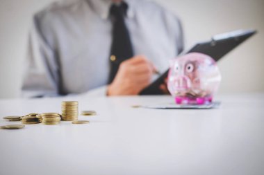 Rapor yazma ve hesap makinesi analizi iş yatırım stratejisi için para sikke ve Doları, mali kavramı gelir ile kullanarak kumbara para koyarak işadamı.