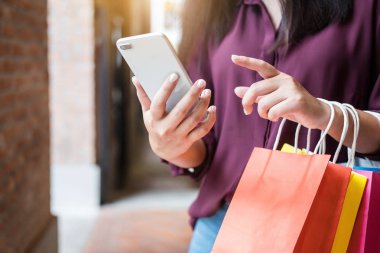 Tüketim, alışveriş, yaşam kavramı, Genç kadın holding renkli alışveriş torbaları ve akıllı telefon Alışveriş keyfi.