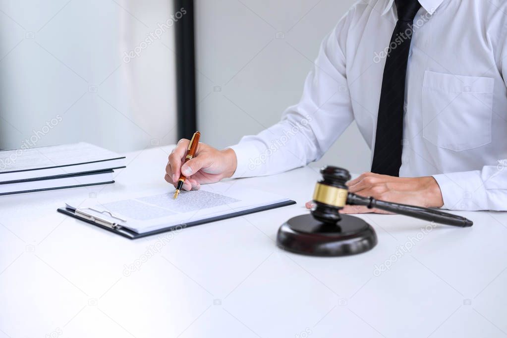 Businessman or lawyer working on a documents, judge gavel with Justice lawyers at law firm in background, Legal law, advice and justice concept.