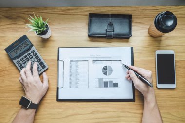 Bir grafik belge mali rapor ve analiz hesaplama maliyet ofis masası, hesap makinesiyle ve diğer nesnelerin çevresine, üstten görünüm çalışma alanı ve boş ekran smartphone üzerinde işadamı.
