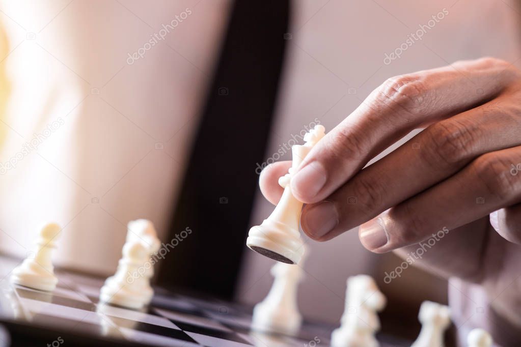 Hand of confident businessman use king chess piece white playing chess game to development analysis new strategy plan, business strategy for win and success.