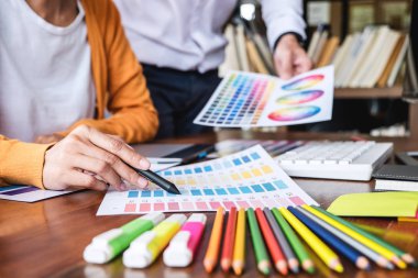 Renk seçimi ve renk örnekleri üzerinde çalışan iki iş arkadaşı yaratıcı grafik tasarımcısı, çalışma araçları ve aksesuarlarla iş yerindeki grafik tabletine çizim yapıyor.
