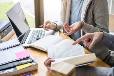 Eğitim, öğretim, öğrenme, teknoloji ve insan kavramı. İki liseli ya da sınıf arkadaşı arkadaşlarıyla birlikte sınıf ödevlerini, ders kitaplarını ve arkadaşlarıyla birlikte yapıyor..