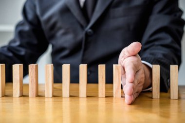 Ahşap oyun stratejisi, iş adamı el durdurma düşen tahta domino etkisi sürekli devrildi veya risk, strateji ve iş için başarılı müdahale kavramı.