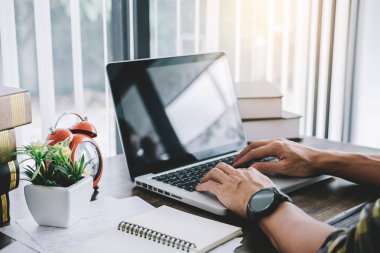 Mutlu rahat Genç Asyalı adam serbest yazar olarak masanın üzerinde bir laptop ve belge rapor kullanarak ev veya küçük ofis çalışma.